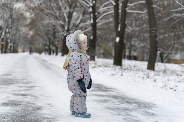 冬天穿雪衣的小女孩在雪地里散步冬季公园天气年轻十二月欢呼