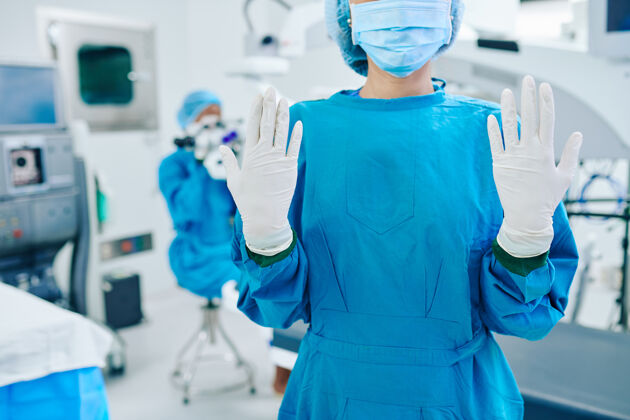 防护剪下的女外科医生在擦洗显示手在橡胶手套保护激光防护面罩矫正