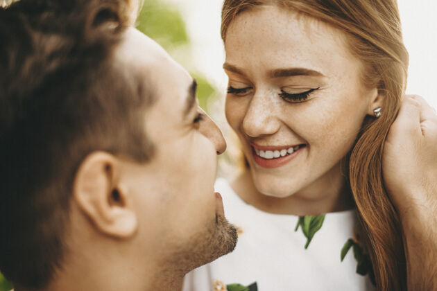漂亮一对美丽的年轻夫妇的特写照片 有雀斑的红发女孩试图亲吻她的男朋友 微笑着抚摸她的红发订婚休闲女朋友
