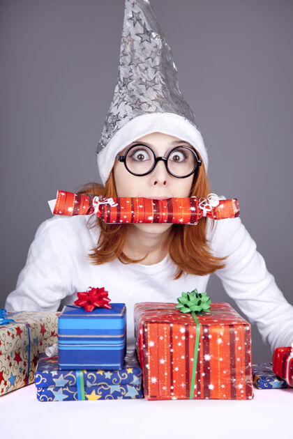 礼物滑稽的红发女孩戴着圣诞帽 戴着带礼盒的眼镜盒子女性可爱