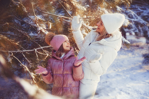 女人妈妈和女儿在冬季公园玩得很开心童年户外父母