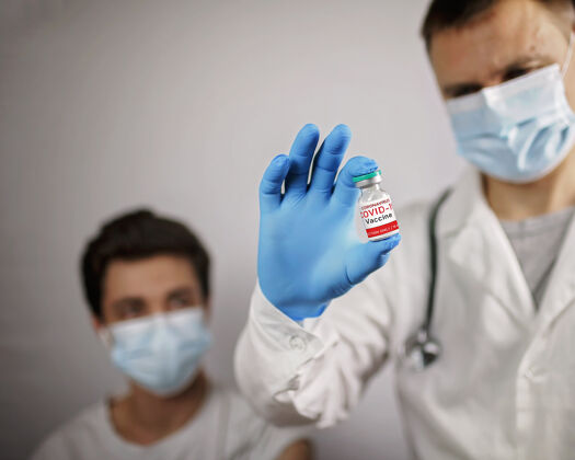 手臂医生戴着医用口罩和手套 拿着装有冠状病毒疫苗的安瓿和注射器病人病毒剂量