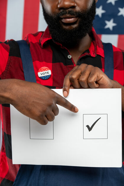 美国文化站在摄像机前 一位年轻的非洲裔美国修理工的手指着选票上一个正方形的记号总统选举制服人民