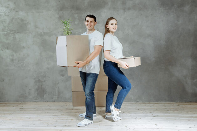 公寓一对微笑的年轻夫妇手拿着搬进新公寓的箱子纸板饱满快乐