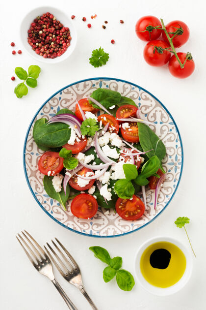 有机西红柿 菠菜叶 红洋葱和乳酪沙拉放在一个浅色的陶瓷盘子里配料温暖菜单