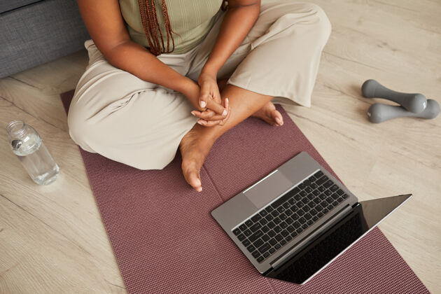 家庭内部特写镜头的年轻女子坐在笔记本电脑前的运动垫和训练与在线体育博客运动垫通讯舒适