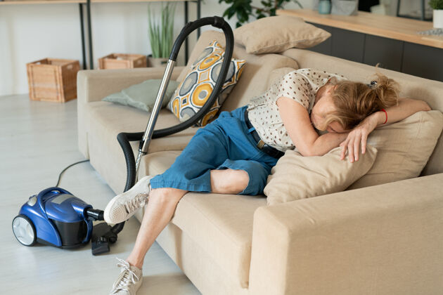 生活方式成熟疲惫的金发女性躺在沙发上柔软的枕头上休息家庭房间快乐欢呼