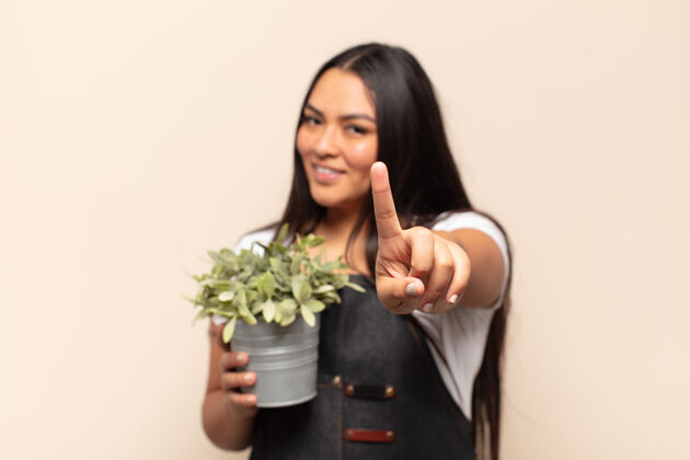 年轻年轻的拉丁女人自豪地微笑着 自信地摆出第一的姿势 感觉像一个领导者植物领导室内植物