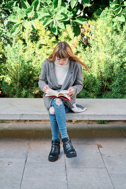 女人一个蓝眼睛的白人金发年轻女子在公园看书教育年轻模特