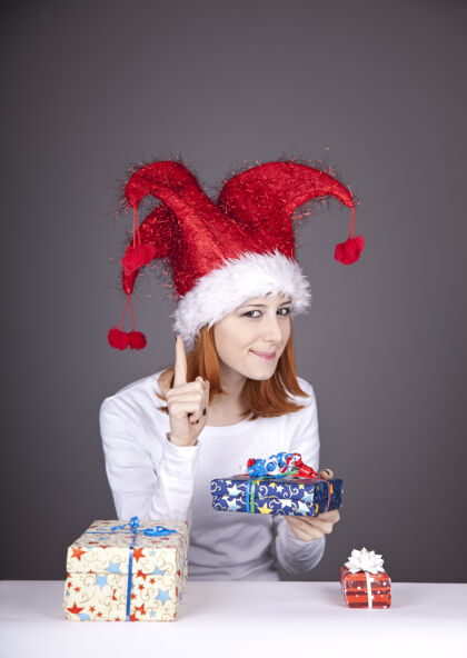 节日滑稽的红发女孩戴着圣诞帽 手里拿着礼品盒携带盒子长