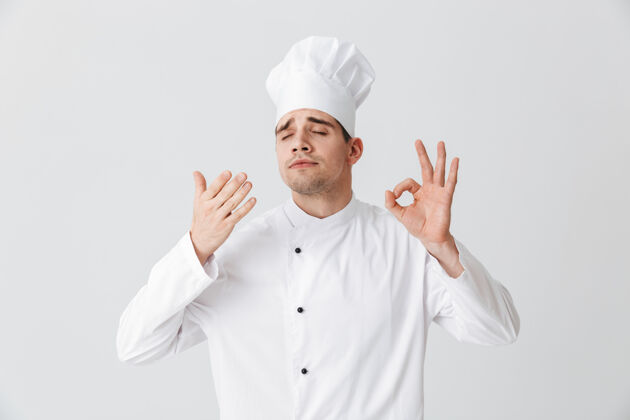 工作服开朗的厨师穿着制服品尝着隔着白墙的味道欢乐烹饪职业