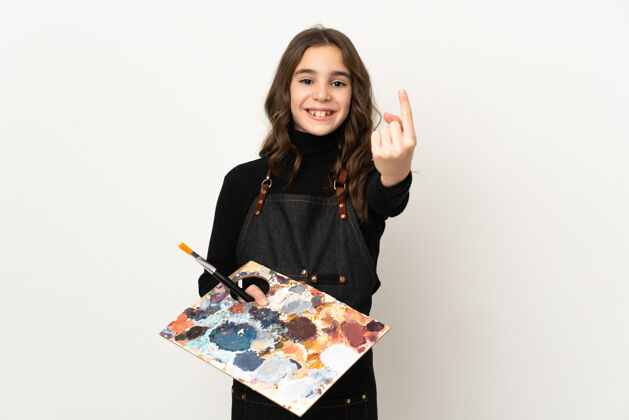 可爱小艺术家女孩拿着一个调色板在白色背景上孤立做即将到来的手势手指邀请电话