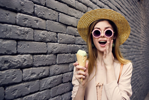 吃戴着太阳镜 手里拿着冰淇淋的开朗女人户外黑砖华尔街风格冰食物人