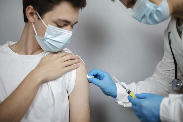 注射医生戴着医用口罩和手套 拿着装有冠状病毒疫苗的安瓿和注射器手臂病人注射