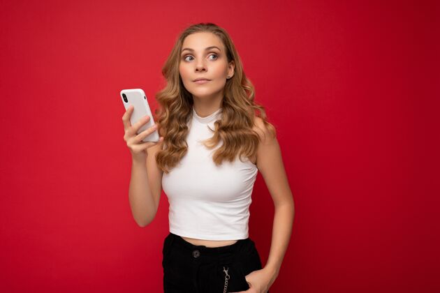 手机穿着白色t恤的快乐的年轻金发女人社交电话短信