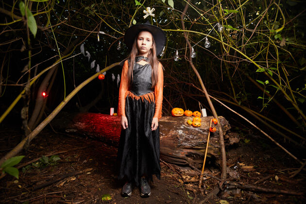 女巫万圣节派对上 穿着女巫服装站在黑暗森林里的小女孩的画像神秘南瓜黑色