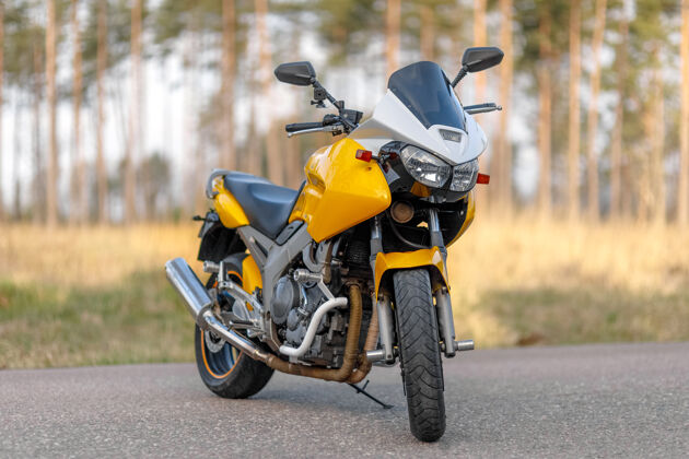 微型黄色摩托车在森林地带的道路上 正面视图复古摩托车道路摩托车手