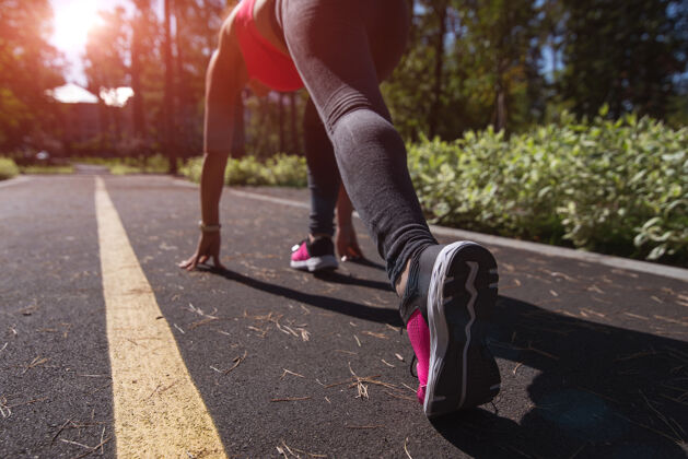有氧运动运动型女跑步者在跑道上的起始位置户外日落或日出的背景健康马拉松城市