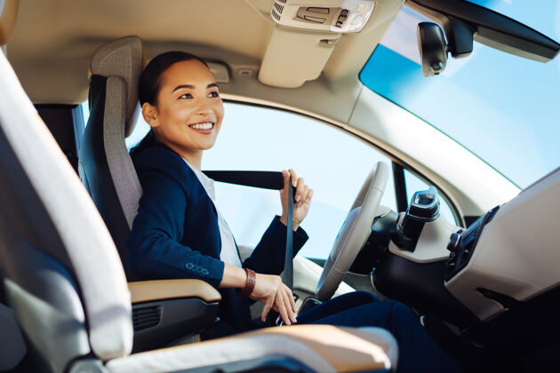 专业在车里快乐积极的女人微笑着系好安全带宽容工作速度