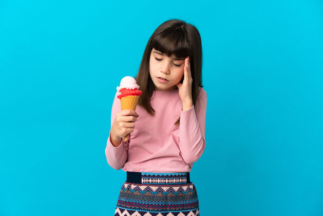 童年拿着短号冰淇淋的小女孩头痛地被隔离在蓝色的墙上不愉快甜点冰