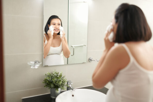 美丽美丽的孕妇在浴室洗脸卫生镜子脸