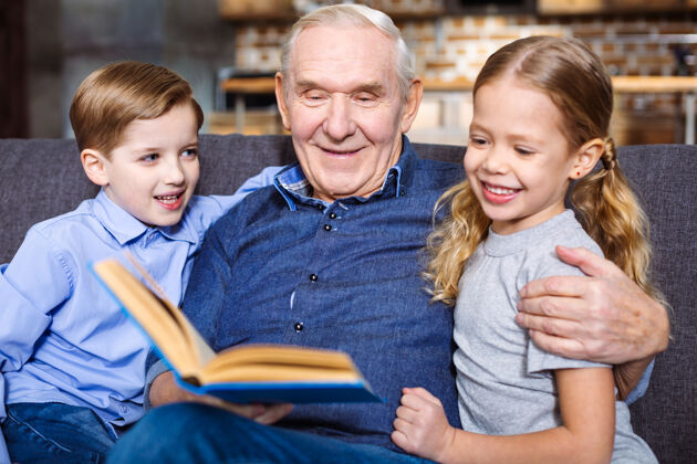 阅读积极的老人一边在家休息一边给孙子们看书休息老人孙子