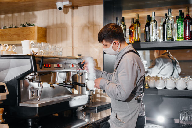 咖啡豆一位蒙面咖啡师在咖啡馆的吧台上准备美味的咖啡这是大流行期间餐馆和咖啡馆的工作咖啡馆服务工人