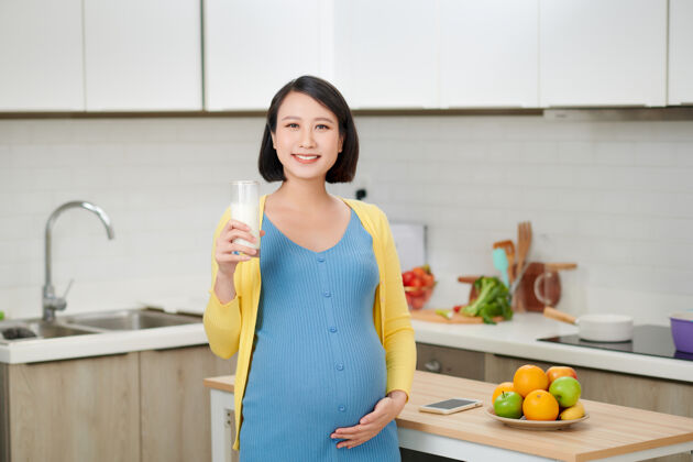 玻璃在厨房喝牛奶的喜气洋洋的女人期望韩国母亲