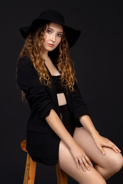 肖像一个穿着内衣 夹克和帽子在黑墙上摆姿势的女人姿势模特女性