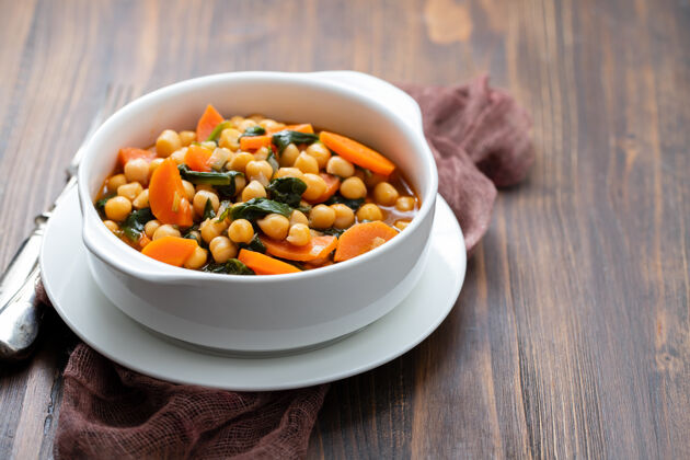 豆类鹰嘴豆配胡萝卜和菠菜 放在白色的碗里 放在棕色的碗里菠菜一餐烘焙
