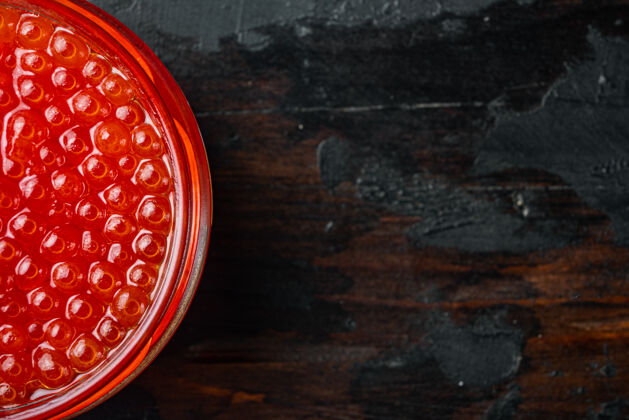 深色木材红色的鲑鱼鱼子酱罐 放在旧的深色木桌上 顶视图平放着复制空间红色鱼子酱玻璃海鲜
