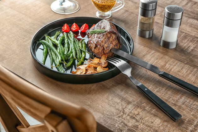 餐厅在木桌上放上美味的烤牛排和蔬菜刀牛排牛肉
