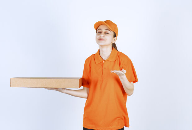 美食身着橙色制服的女快递员拿着外卖披萨盒 闻着产品的味道模型员工促销