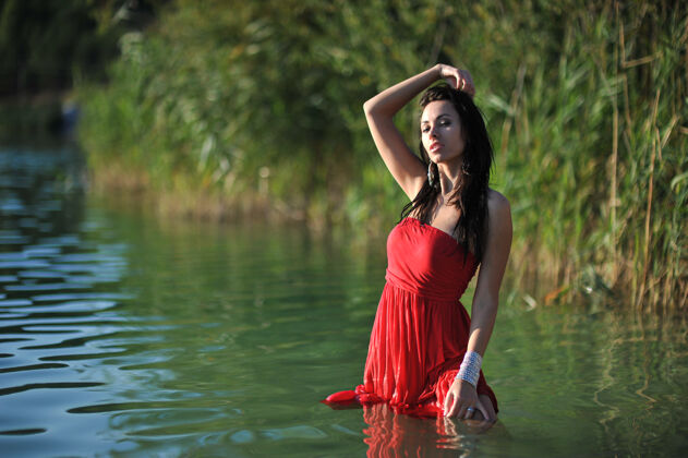 浪漫夏天的年轻女子红色长裙在户外摆姿势时髦年轻风