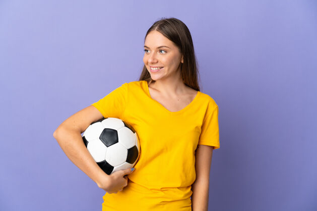 球员年轻的立陶宛足球运动员女子孤立在紫色背景看一边专业运动积极