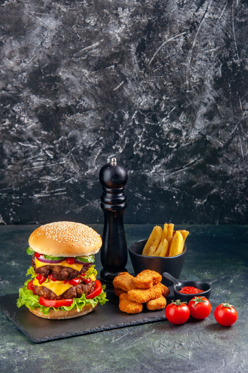 健康美味的三明治和鸡块薯条在深色托盘上西红柿在黑色的表面在垂直视图水果薯条番茄