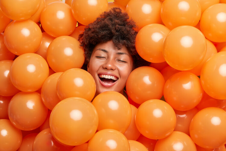民族女人表达积极的情绪闭上眼睛微笑着被膨胀的气球包围非洲乐趣牙关