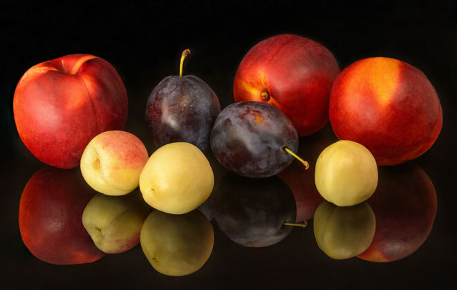 颜色黑色背景上的新鲜油桃和李子李子多汁水果