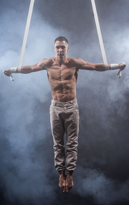 肌肉马戏团艺术家在空中肩带与强大的肌肉黑色平衡动作腰带