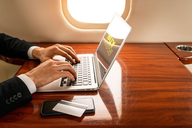 电脑英俊的商人穿着优雅的西装乘坐私人专机飞行网上购物笔记本电脑旅行