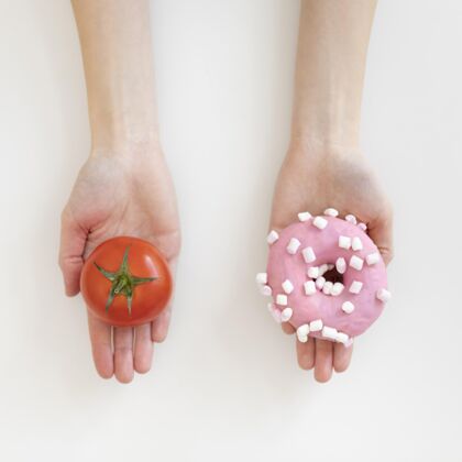 饮食双手紧握着甜甜圈和西红柿健康食品女人