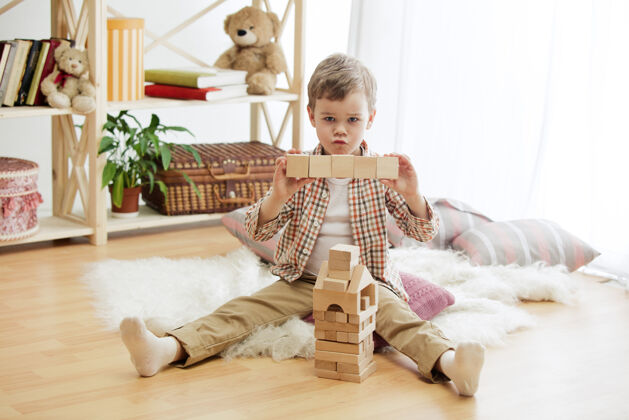 乐趣坐在地板上的小孩漂亮的男孩在家里玩木制立方体概念图像与复制或负空间和模拟你的文字学习幼儿玩具