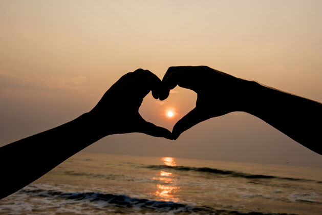 日落这个剪影是在日落时用手塑造的心形爱形状情人