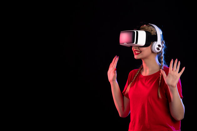 玩在黑暗的视觉上 年轻女士戴着耳机玩虚拟现实的肖像漂亮虚拟现实小姐