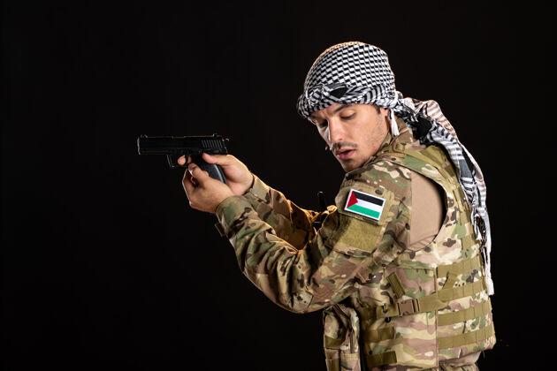 人巴勒斯坦士兵用枪瞄准黑墙制服成人男人