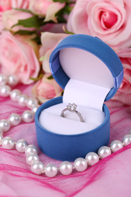 花玫瑰和粉红布上的订婚戒指花束浪漫开花