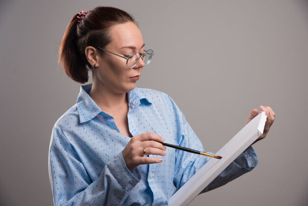 笔女人用灰色的画笔在画布上画东西眼镜休闲情感