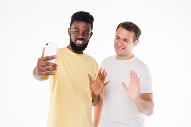 人两个混血男人用智能手机摄像头在白墙上自拍科技拉丁休闲