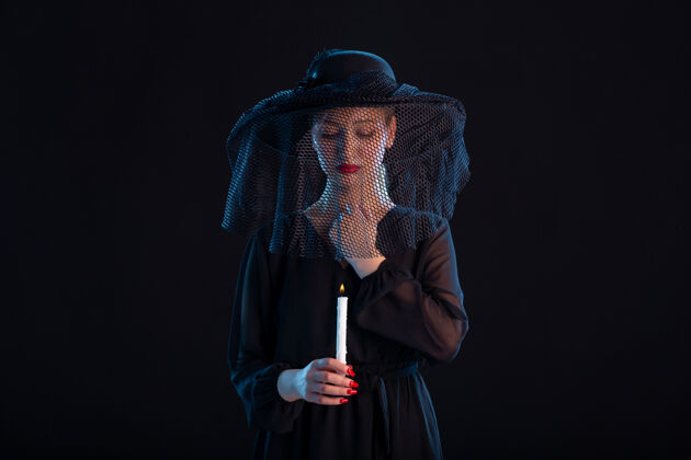 葬礼悲伤的女子穿着黑色的衣服 用燃烧的蜡烛在黑色的悲伤葬礼上死去衣服麦克风火灾
