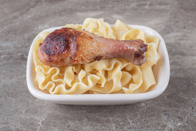 面食烤鸡腿放在意大利面上 放在大理石表面鸡腿碗好吃的